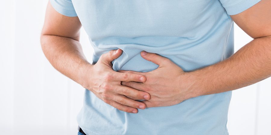 Close-up Of Young Man Suffering From Stomach Ache Standing At Home