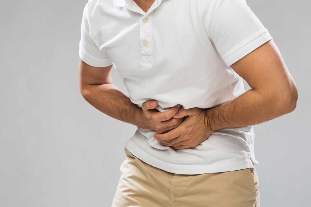 close up of man suffering from stomach ache over gray background