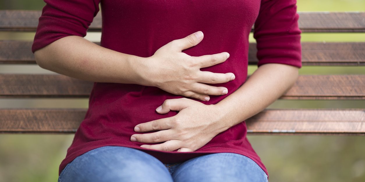 Woman Has Stomach Ache Sitting on Bench at Park