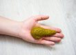 In palm of hand lying on wooden floor, is anatomical model of pancreas gland. Concept photo depicting pancreas illness such as cancer as cause of death, organ donation after death of patient