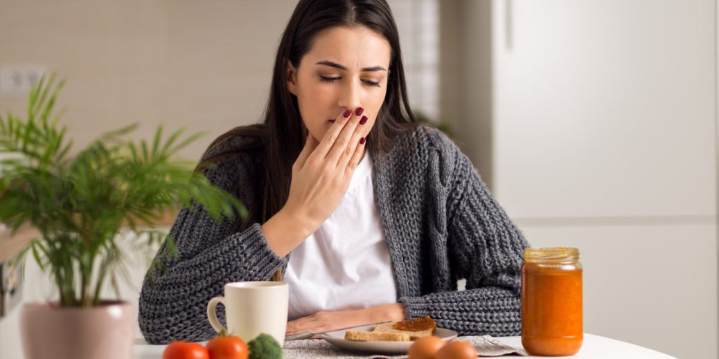 young woman covering mouth with hand in front of breakfast