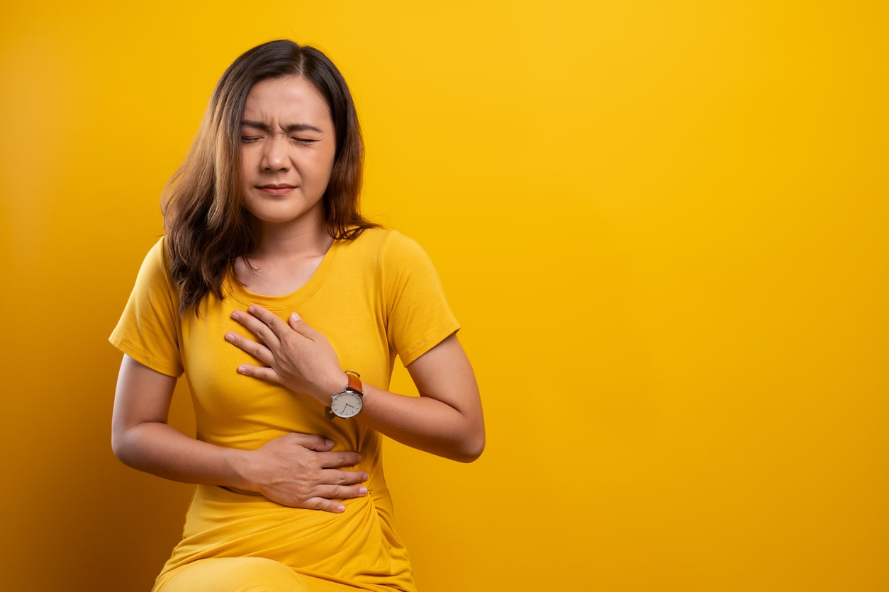 Woman in yellow experiencing acid reflux