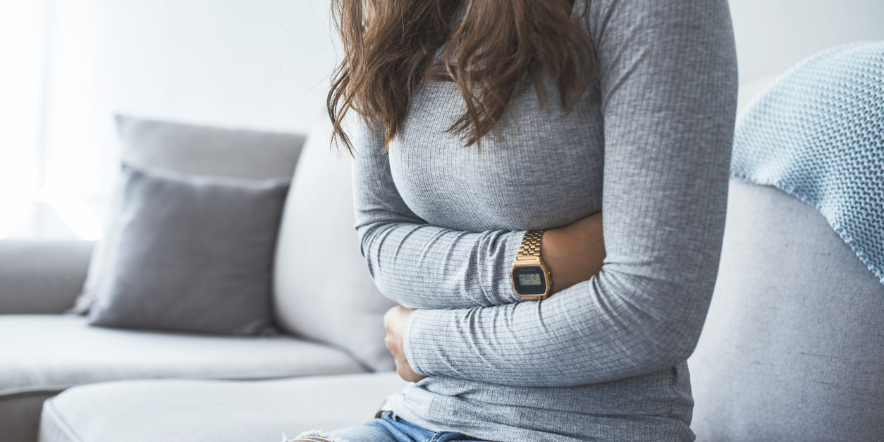 Woman holding stomach with ulcerative colitis pain