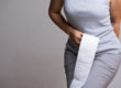Woman with toilet paper experiencing hemorrhoid pain