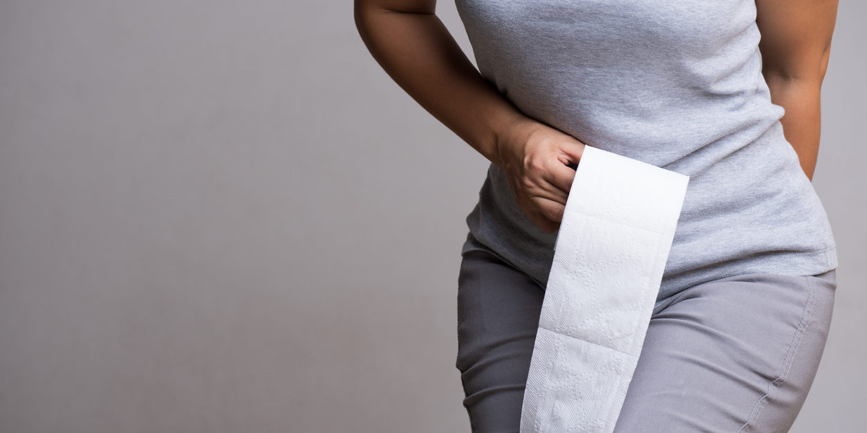 Woman with toilet paper experiencing hemorrhoid pain