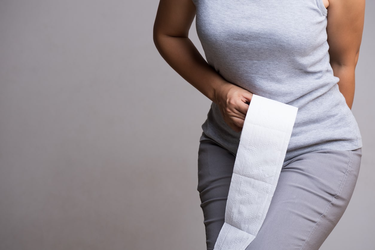 Woman with toilet paper experiencing hemorrhoid pain