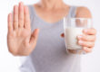 woman holding glass of milk, and holding her hand up