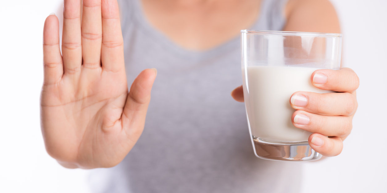 woman holding glass of milk, and holding her hand up