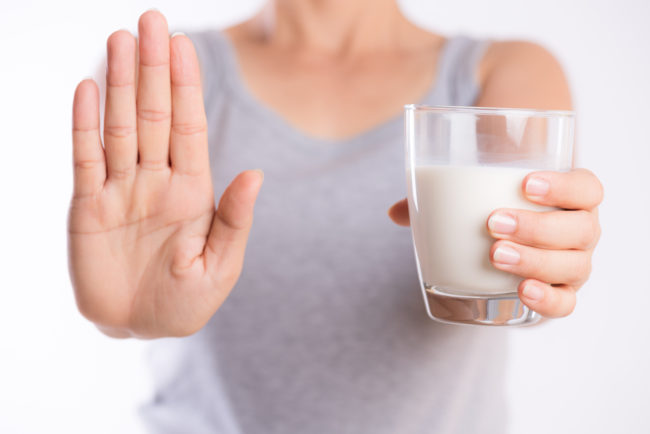 woman holding glass of milk, and holding her hand up