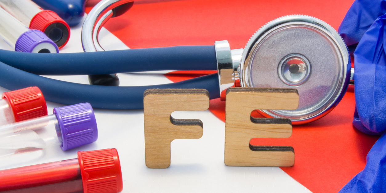 stethoscope and other medical instruments on table with the letters "fe" to connotate the element iron