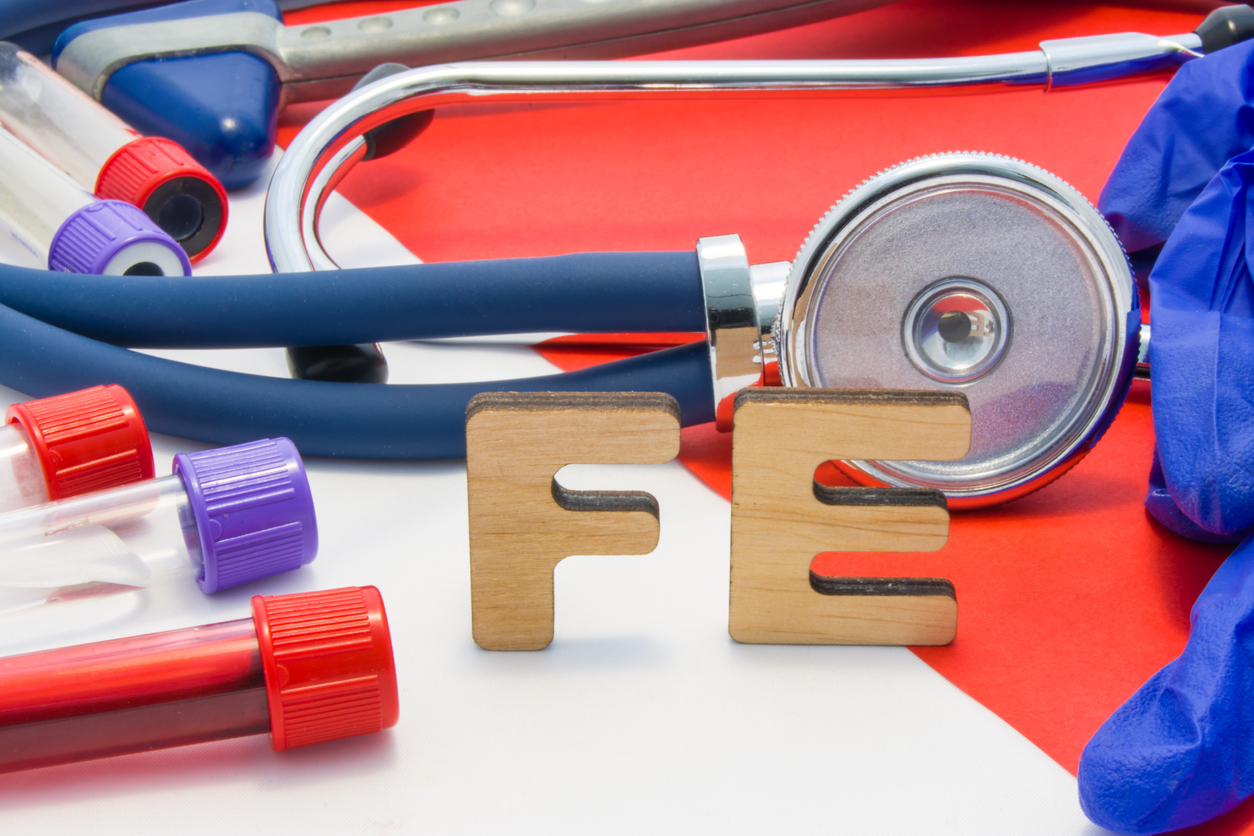 stethoscope and other medical instruments on table with the letters "fe" to connotate the element iron