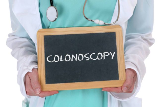 doctor holding small chalkboard with the word "colonoscopy"